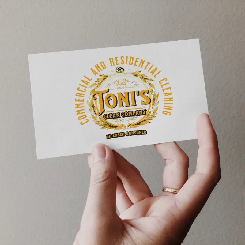 Gold Toni's Clean Company crest logo printed on a business card held in a hand